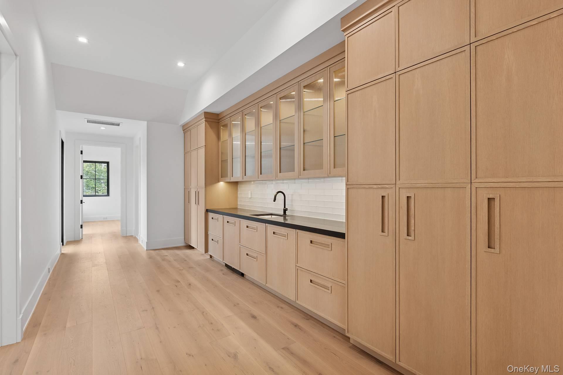 150 Edge Of Woods Road Southampton, NY 11968 - Photo 28 of 47 a large white kitchen with white cabinets and sink