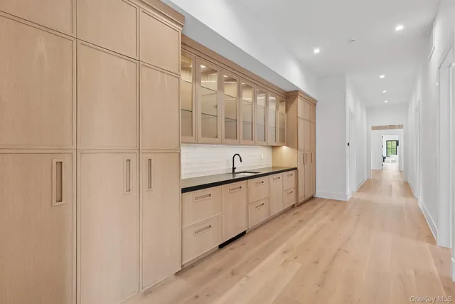 a large white kitchen with granite countertop a sink and dishwasher a stove with wooden floors