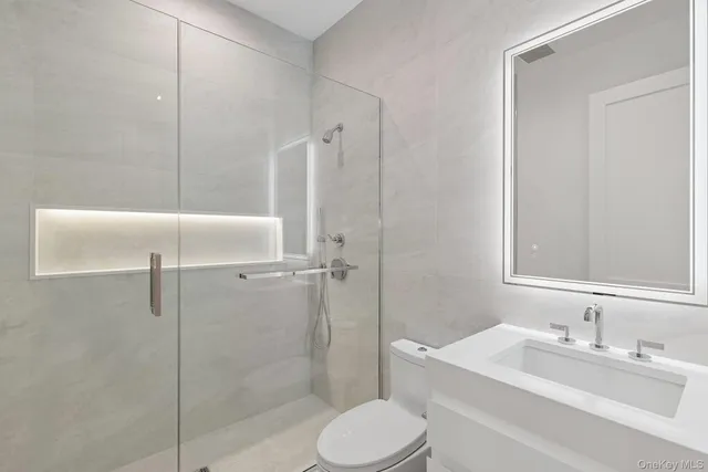 a bathroom with a toilet sink vanity granite and shower