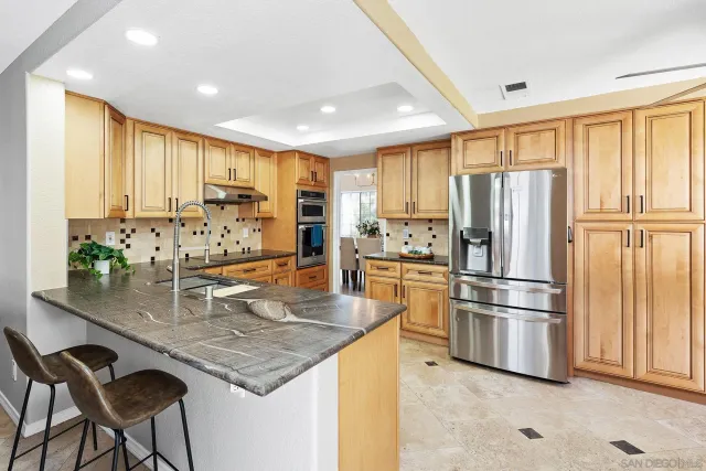 a kitchen with stainless steel appliances granite countertop a refrigerator a stove and white cabinets with wooden floor