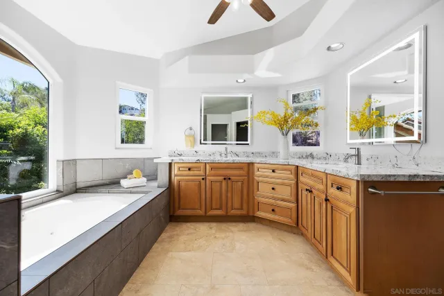 a spacious bathroom with a granite countertop sink mirror and bathtub