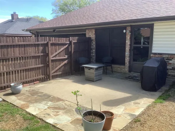 a backyard of a house with wooden fence and a potted plant