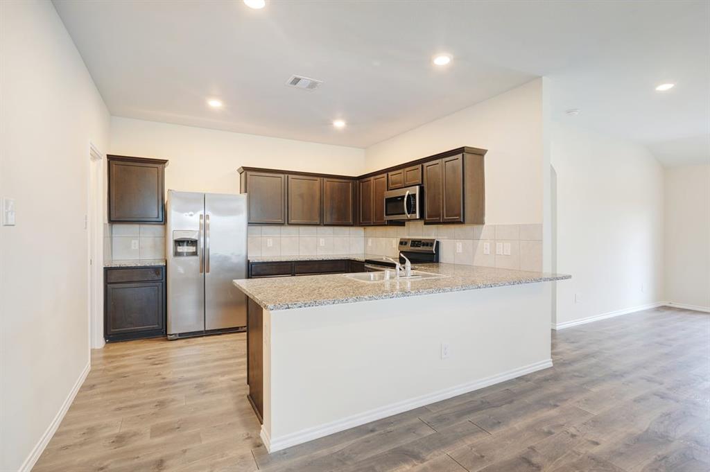 2328 Stefani Street Anna, TX 75409 - Photo 7 of 23 a large kitchen with stainless steel appliances granite countertop a sink and a refrigerator