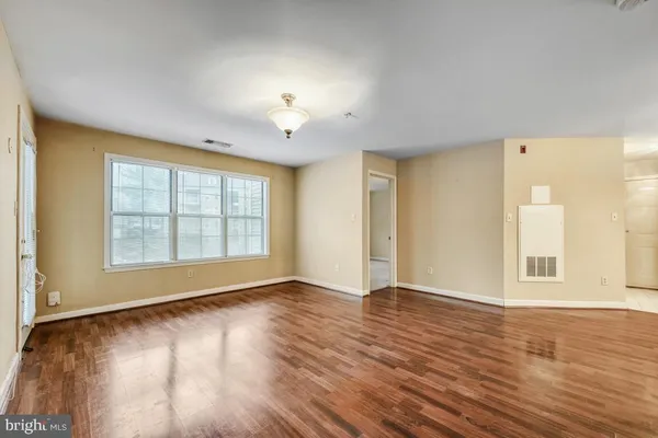 an empty room with wooden floor and windows