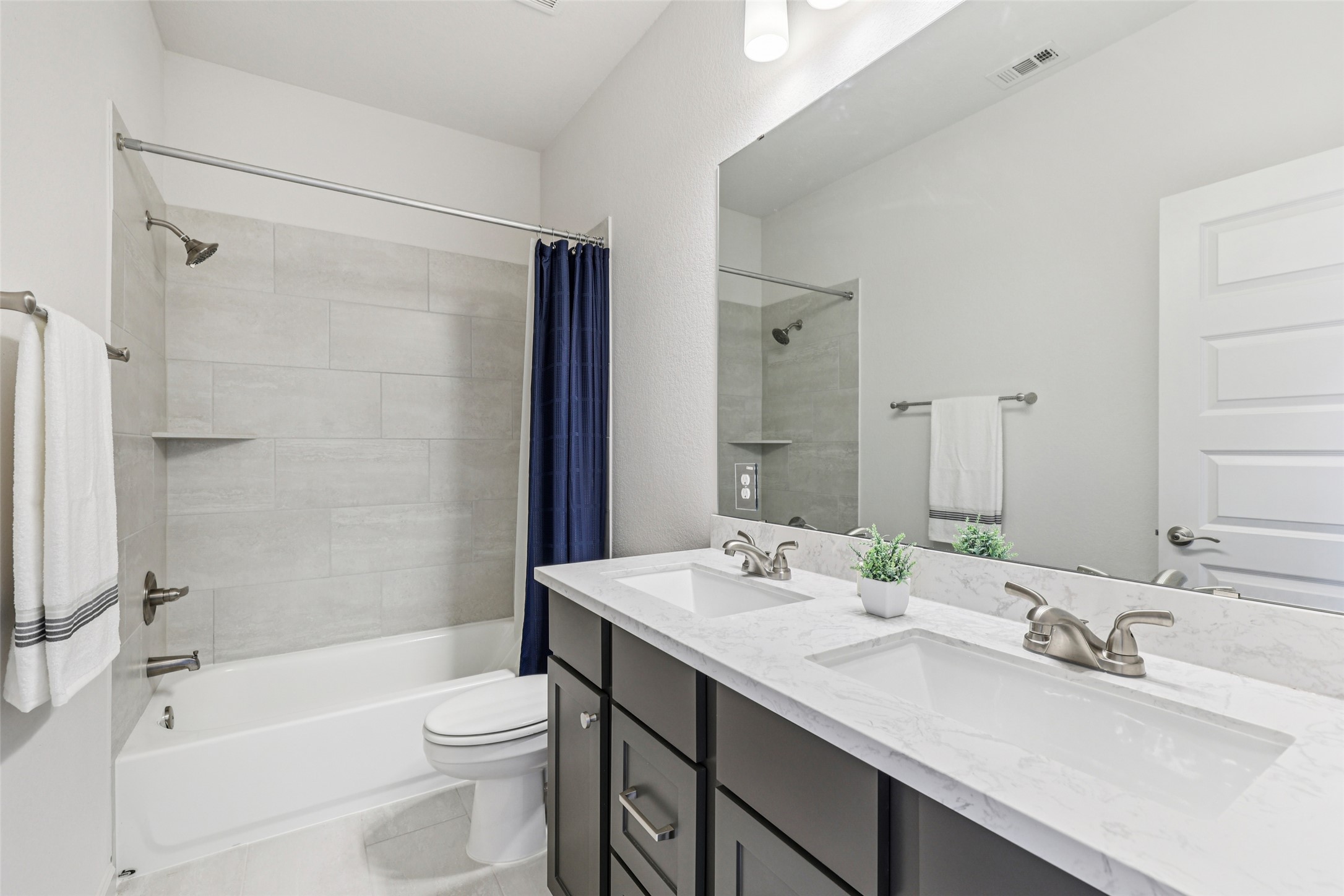 1140 Bryson Rdg Trail Leander, TX 78641 - Photo 30 of 39 Bathroom featuring a dual vanity with white countertops, a bathtub with light gray tiled walls, and a large mirror