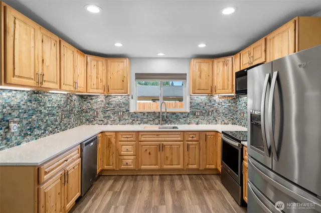 a kitchen with stainless steel appliances granite countertop a sink and wooden cabinets
