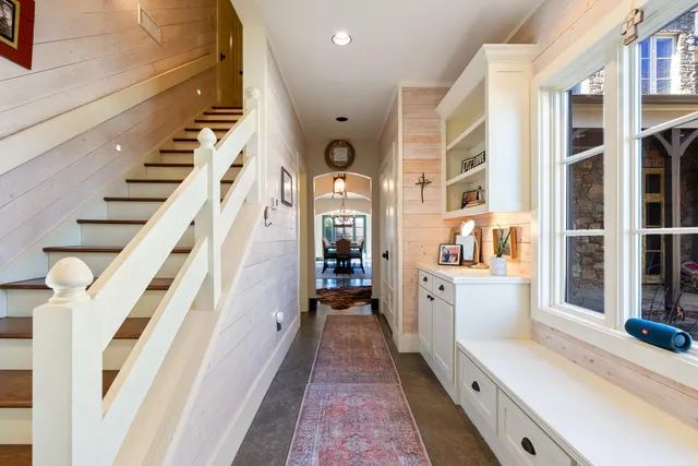 a hallway with white cabinets and chandelier