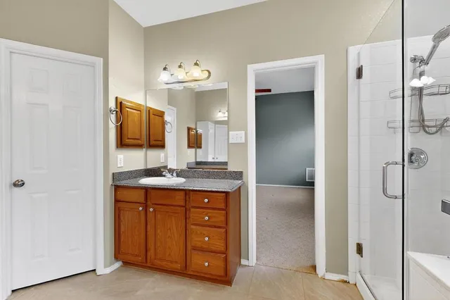 a bathroom with a granite countertop sink a mirror and a shower