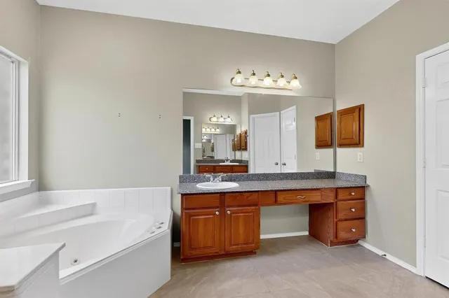 a bathroom with a tub a double vanity sink and a large mirror