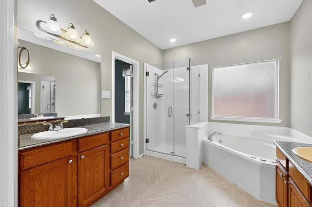 a spacious bathroom with a double vanity sink a large mirror a bathtub and shower