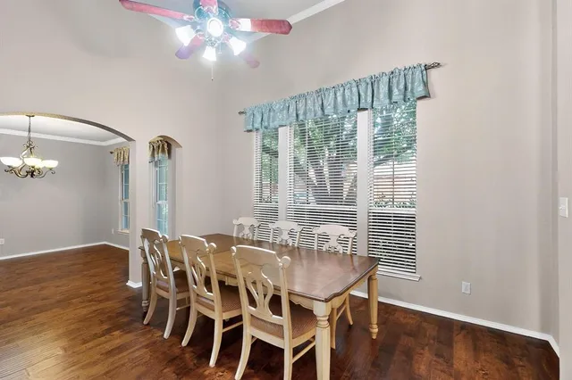 a dining room with wooden floor a chandelier a glass table and chairs