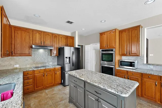 a kitchen with stainless steel appliances granite countertop a sink refrigerator and microwave