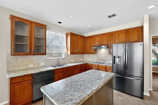 a kitchen with stainless steel appliances granite countertop a refrigerator a sink and a stove