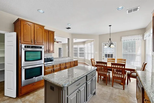 a kitchen with stainless steel appliances granite countertop a stove top oven a sink a dining table and chairs