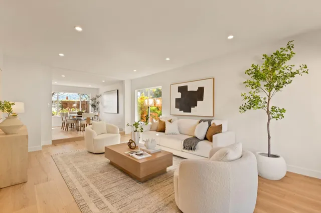 a living room with furniture large window and wooden floor