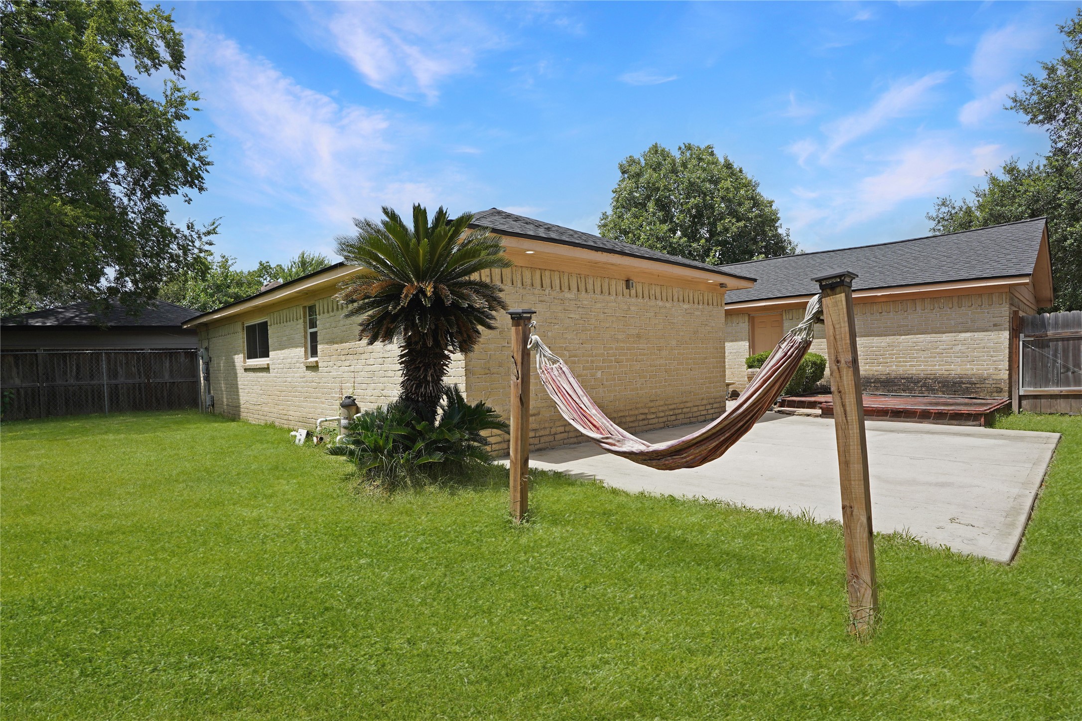 17119 Mellow Ridge Drive Spring, TX 77379 - Photo 28 of 32 Charming backyard with lush grass, a cozy hammock, and a patio area, perfect for relaxation and outdoor activities.