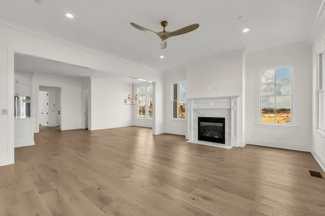 an empty room with wooden floor a fireplace and windows