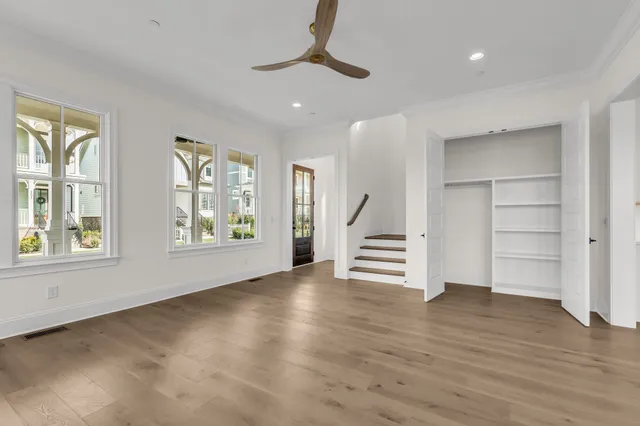 an empty room with wooden floor staircase and windows