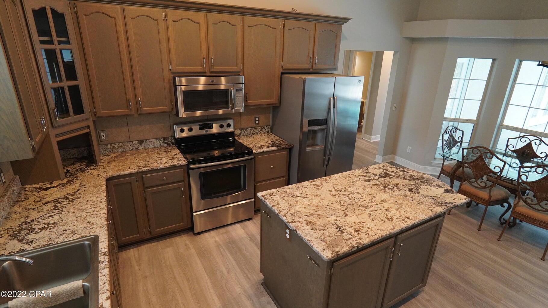104 Colony Harbour Road Panama City Beach, FL 32407 - Photo 27 of 75 a kitchen with stainless steel appliances granite countertop a stove refrigerator and microwave