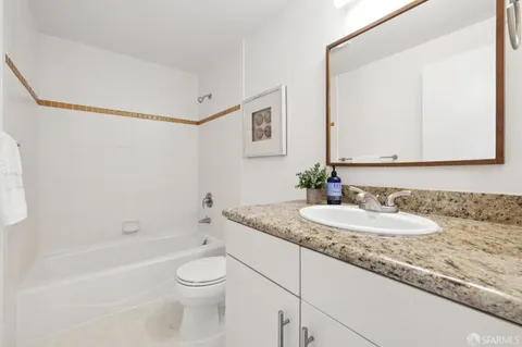 a bathroom with a granite countertop sink a toilet and bathtub