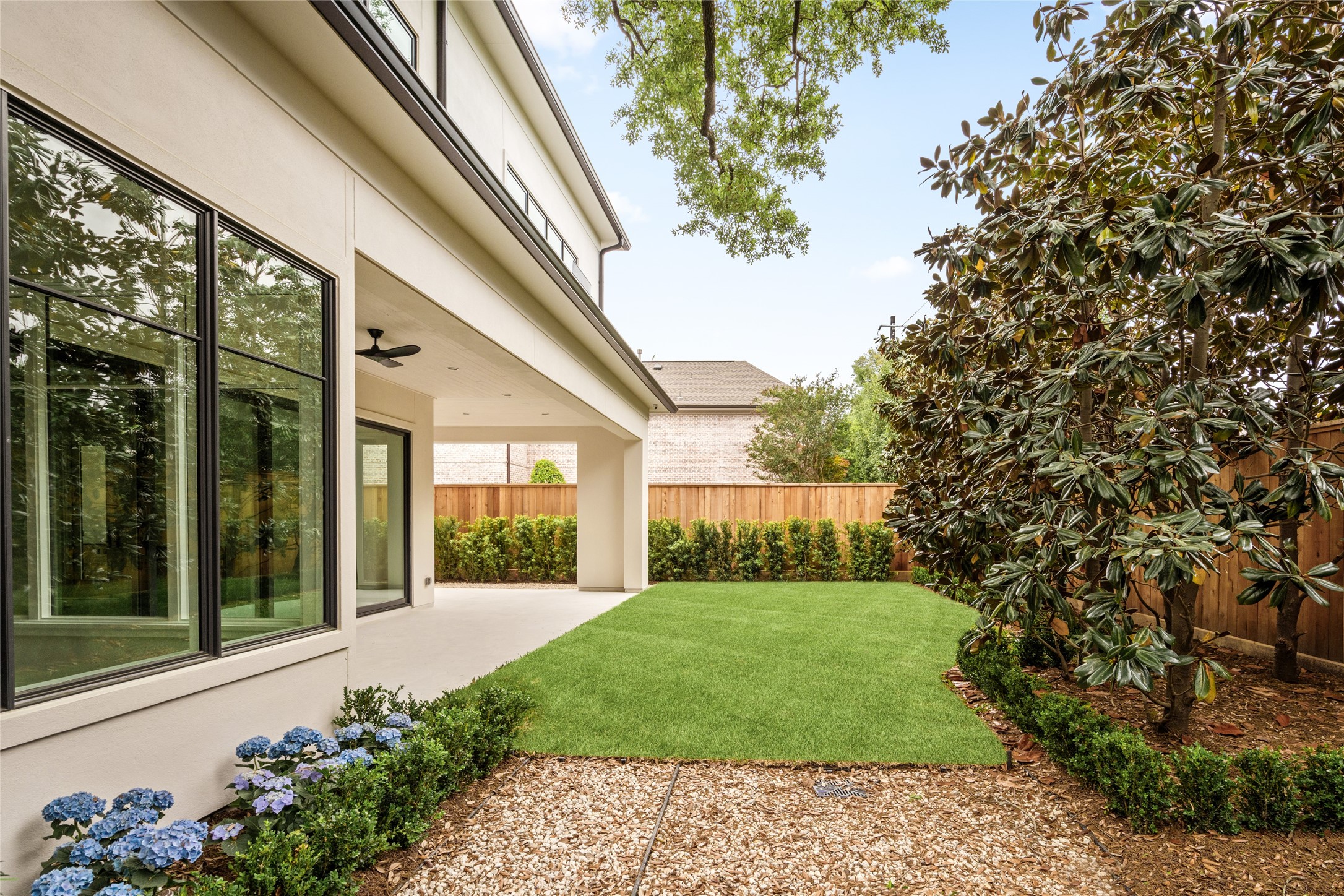 4006 Overbrook Lane Houston, TX 77027 - Photo 49 of 50 Another look at the thoughtfully landscaped grounds with wall of mature trees, clean hardscaping, and covered outdoor living extending from the home.