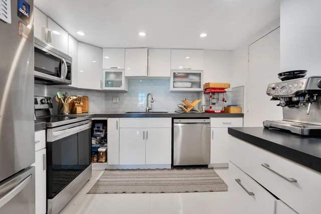 a kitchen with white cabinets and appliances