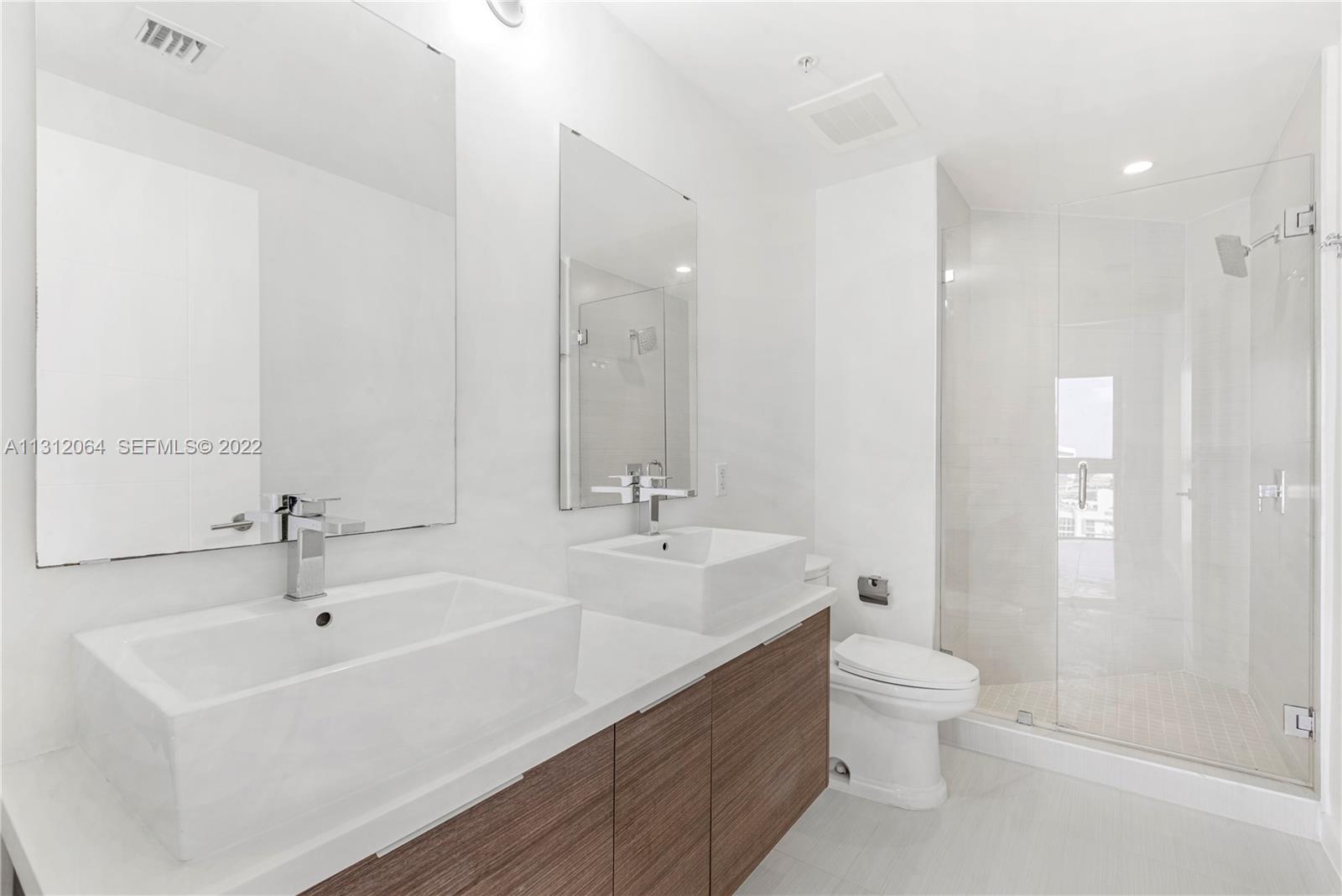 1010 Southwest 2nd Avenue, Unit 2004 Miami, FL 33130 - Photo 12 of 19 a bathroom with a double vanity sink toilet and a mirror