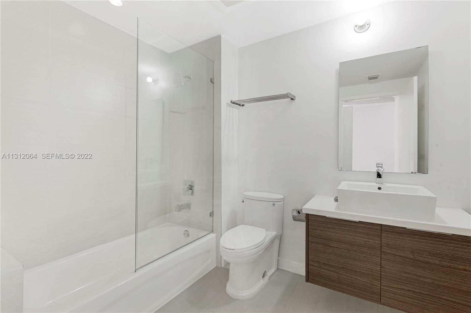 1010 Southwest 2nd Avenue, Unit 2004 Miami, FL 33130 - Photo 13 of 19 a bathroom with a double vanity sink toilet mirror and bathtub