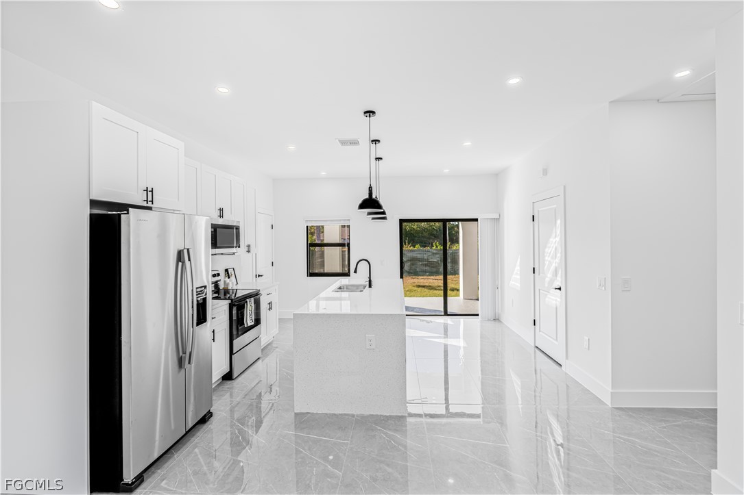 745 Roma Avenue South Lehigh Acres, FL 33974 - Photo 13 of 40 a kitchen with stainless steel appliances kitchen island granite countertop a refrigerator and a stove top oven