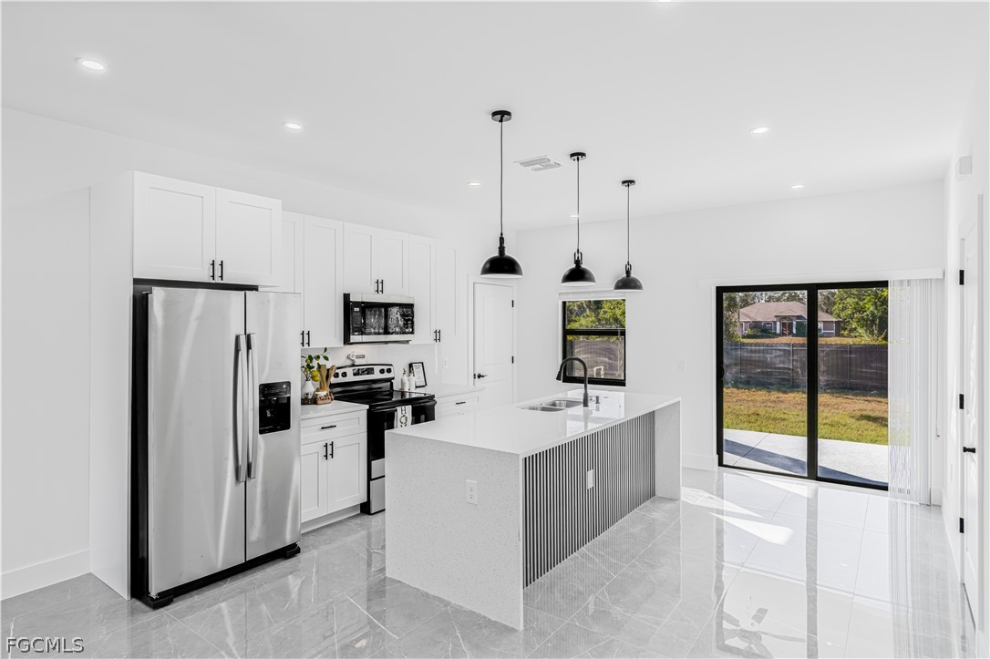 745 Roma Avenue South Lehigh Acres, FL 33974 - Photo 14 of 40 a kitchen with stainless steel appliances kitchen island granite countertop a refrigerator and a sink