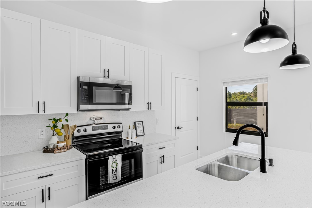 745 Roma Avenue South Lehigh Acres, FL 33974 - Photo 17 of 40 a kitchen with stainless steel appliances a stove a sink and a microwave