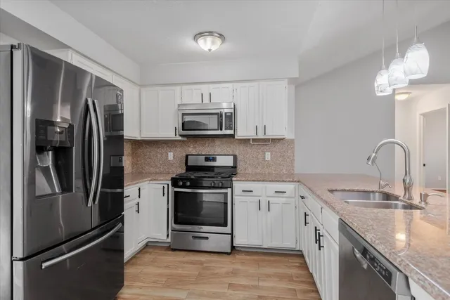 a kitchen with stainless steel appliances granite countertop a refrigerator stove and sink