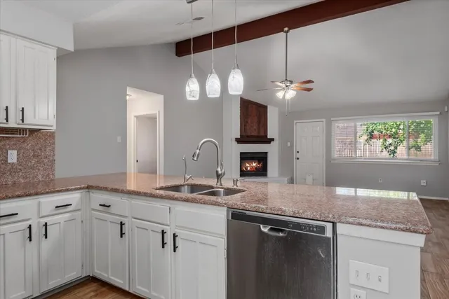 a kitchen with stainless steel appliances granite countertop a sink a stove and a granite counter tops with white cabinets