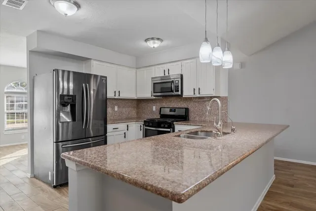 a kitchen with stainless steel appliances granite countertop a refrigerator a stove top oven a sink and dishwasher