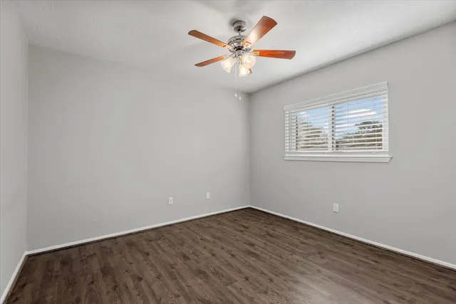 an empty room with wooden floor and ceiling fan
