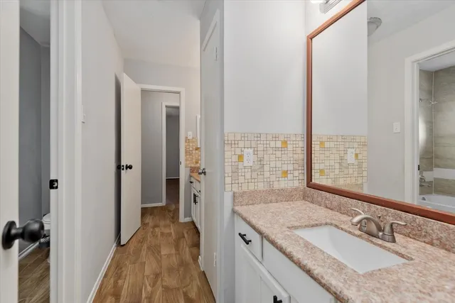 a bathroom with a granite countertop sink a mirror and a shower