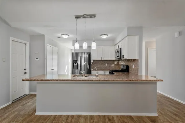a large white kitchen with kitchen island granite countertop a large counter top and sink