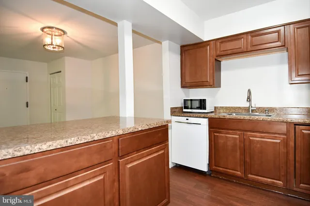 a kitchen with granite countertop cabinets stainless steel appliances and a wooden floor