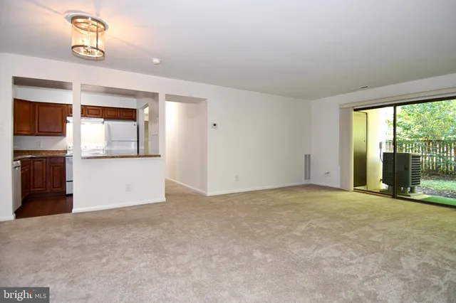 an empty room with a kitchen view and a window