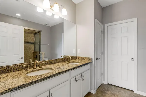 a bathroom with a granite countertop double vanity sink and a mirror
