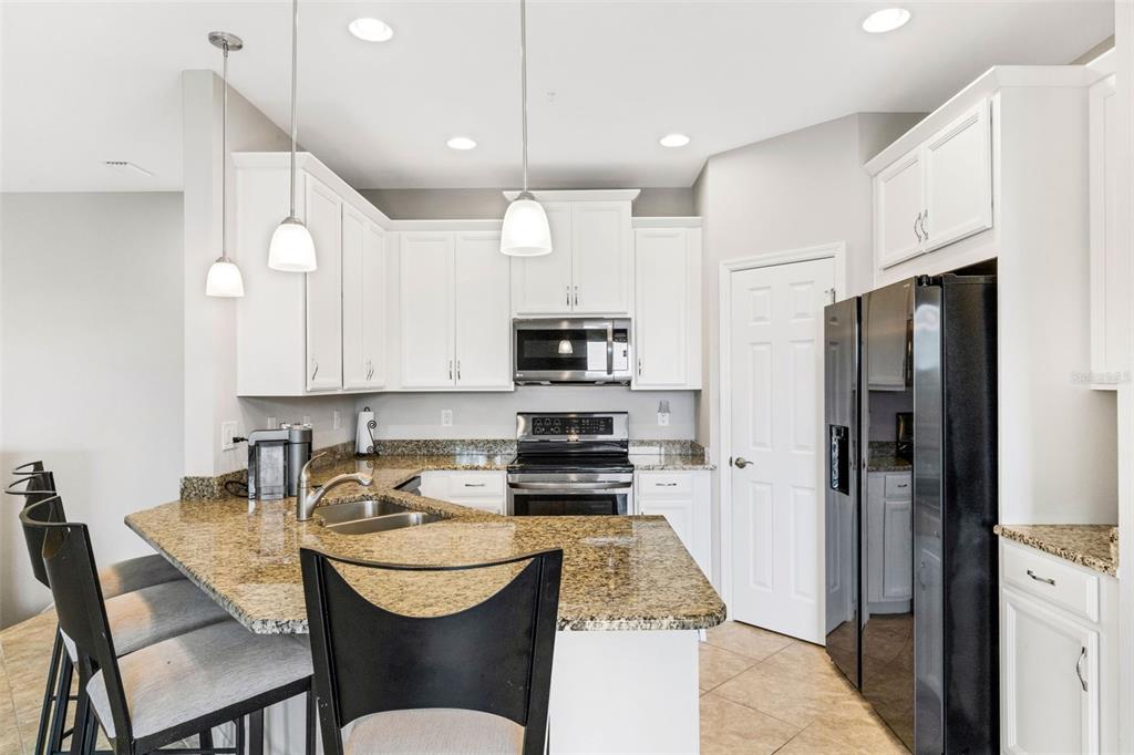 4284 Expedition Way Osprey, FL 34229 - Photo 9 of 40 a kitchen with stainless steel appliances kitchen island granite countertop a refrigerator a stove a sink a dining table and chairs with wooden floor