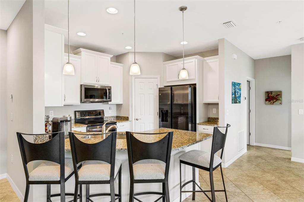 4284 Expedition Way Osprey, FL 34229 - Photo 10 of 40 a kitchen with stainless steel appliances kitchen island granite countertop a dining table chairs and a refrigerator