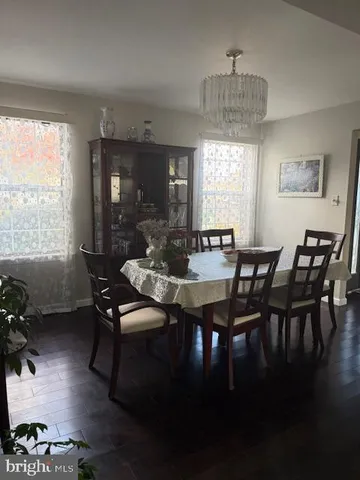 a kitchen with stainless steel appliances a sink dishwasher a refrigerator and a dining table with wooden floor