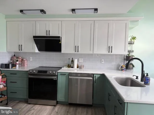 a kitchen with stainless steel appliances kitchen island a refrigerator a sink a stove and cabinets