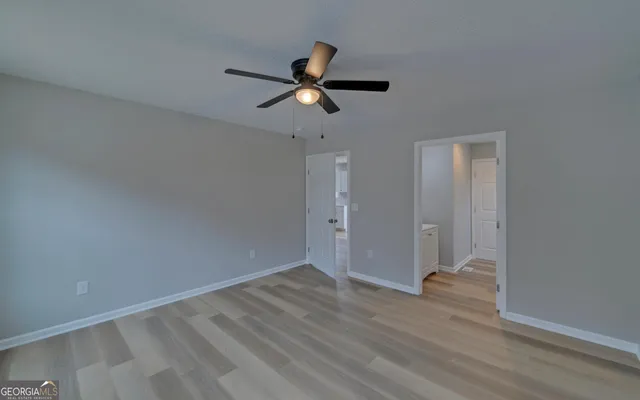 a view of a room with wooden floor and a ceiling fan