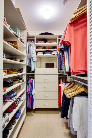 a view of walk in closet with clothes and shoes