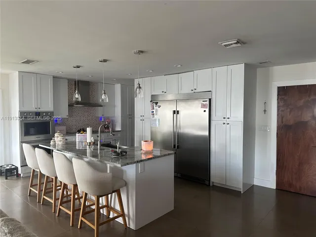 a kitchen with stainless steel appliances a refrigerator a stove a sink dishwasher and a dining table with wooden floor