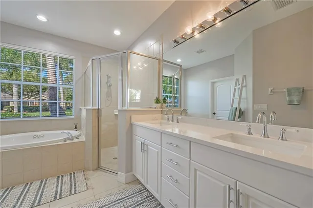 a spacious bathroom with a double vanity sink a large mirror and a bathtub