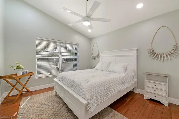 a large bedroom with a bed and a dresser with wooden floor