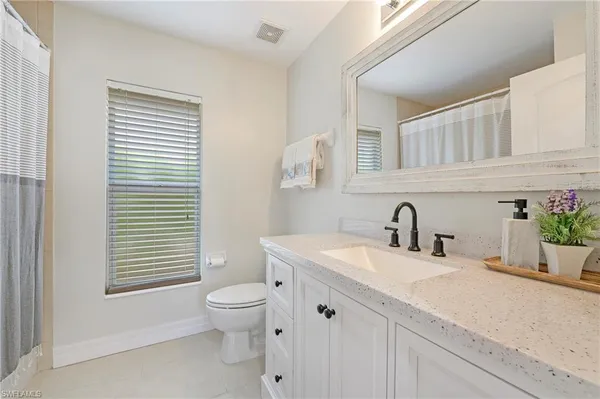 a bathroom with a granite countertop sink toilet and mirror